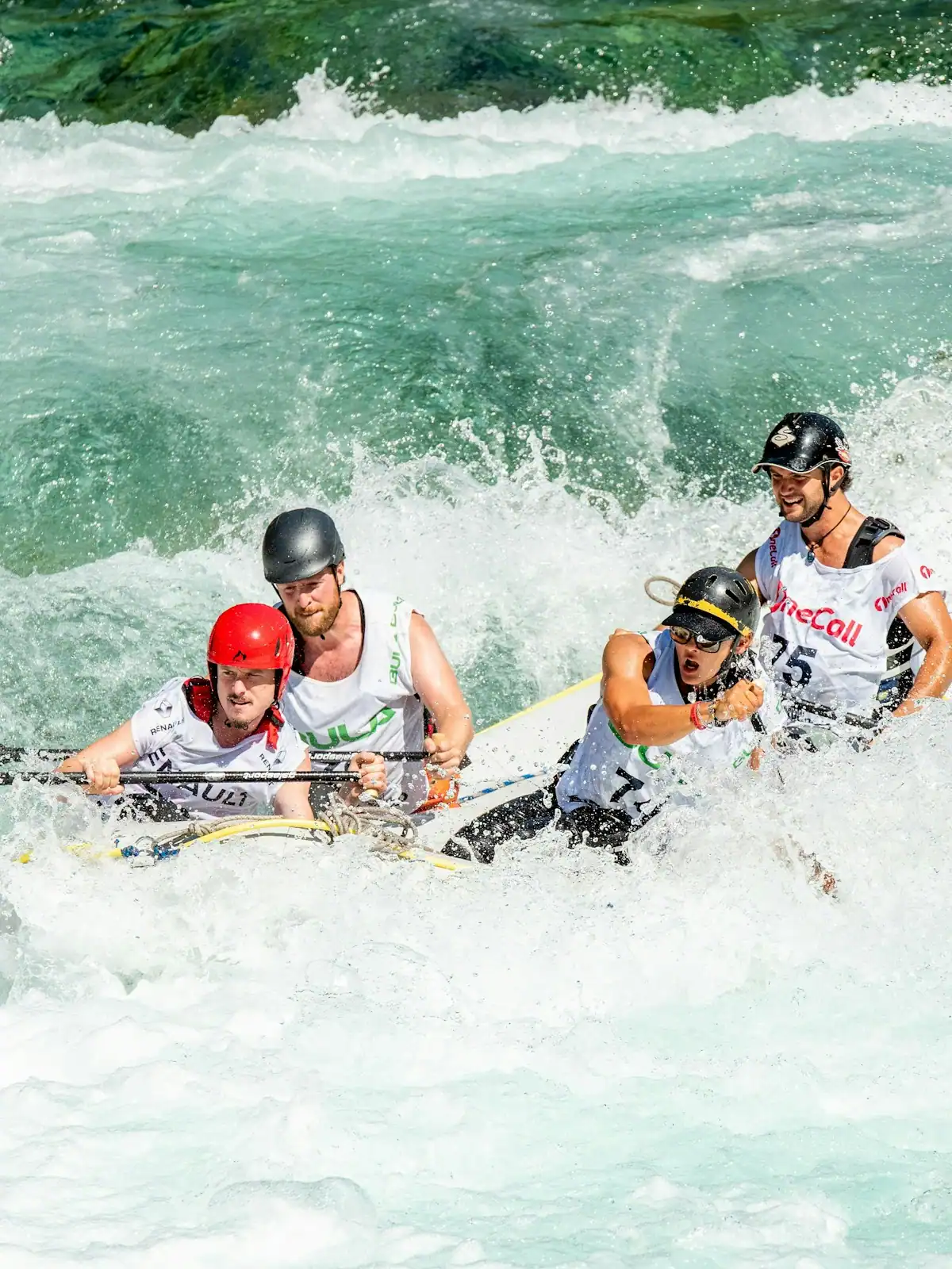 Whitewater breaking over boulders in a fast river between wooded banks